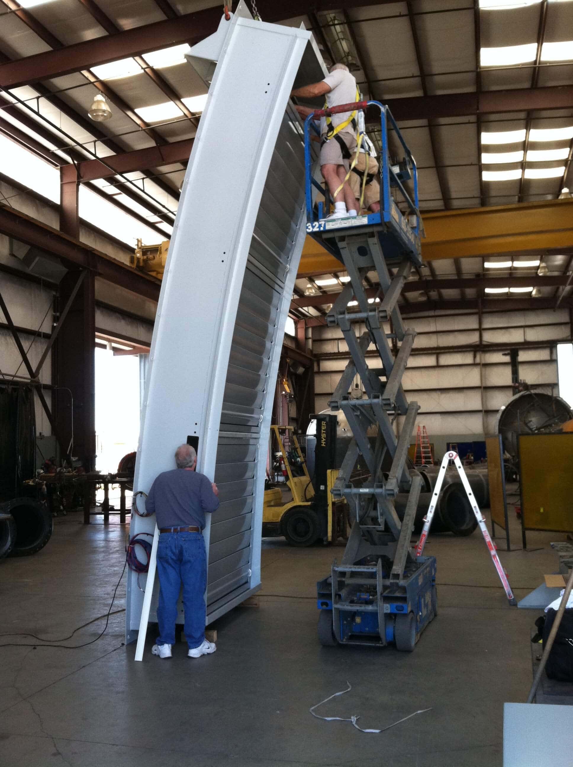 technicians applying giant shutter to telescope frame
