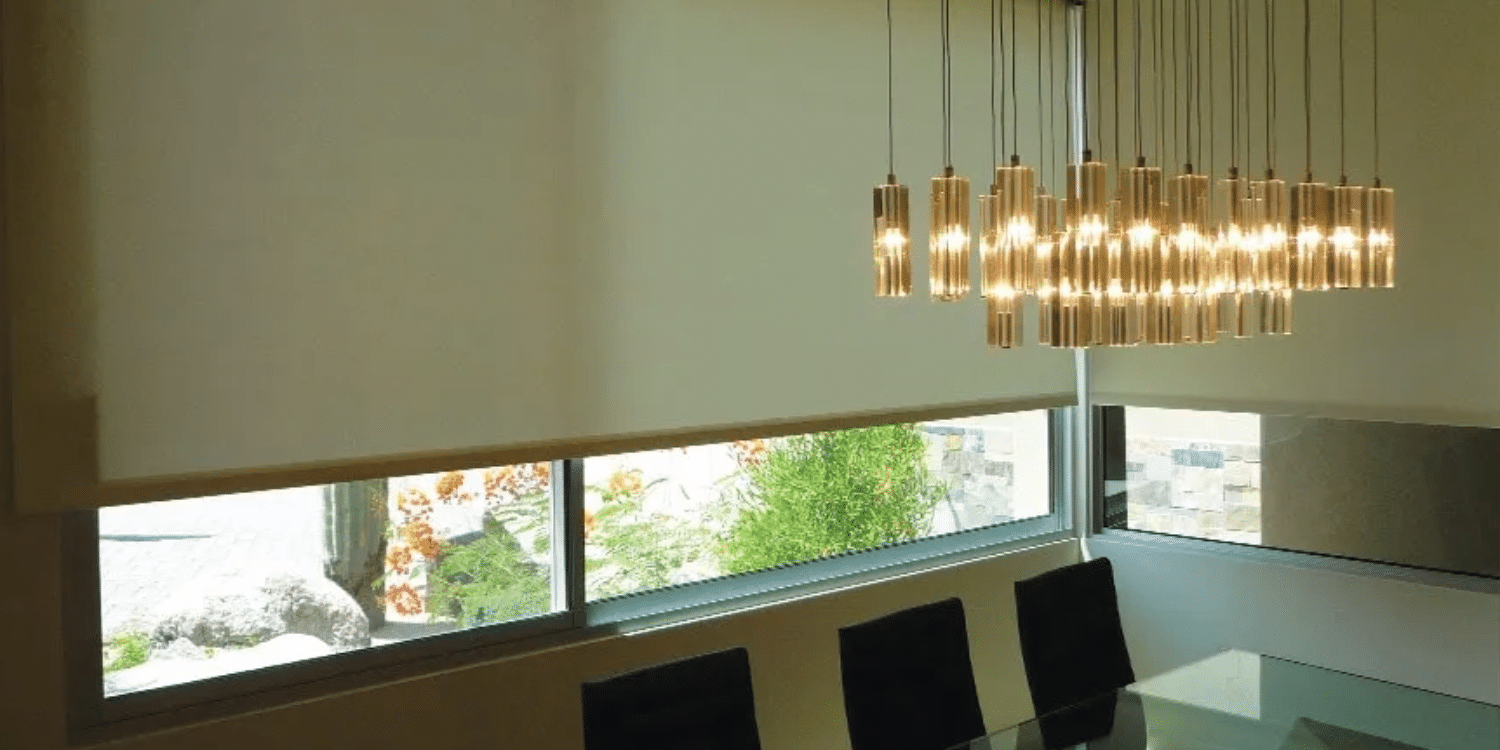 White window shades covering most of a dining room behind the dining room table.